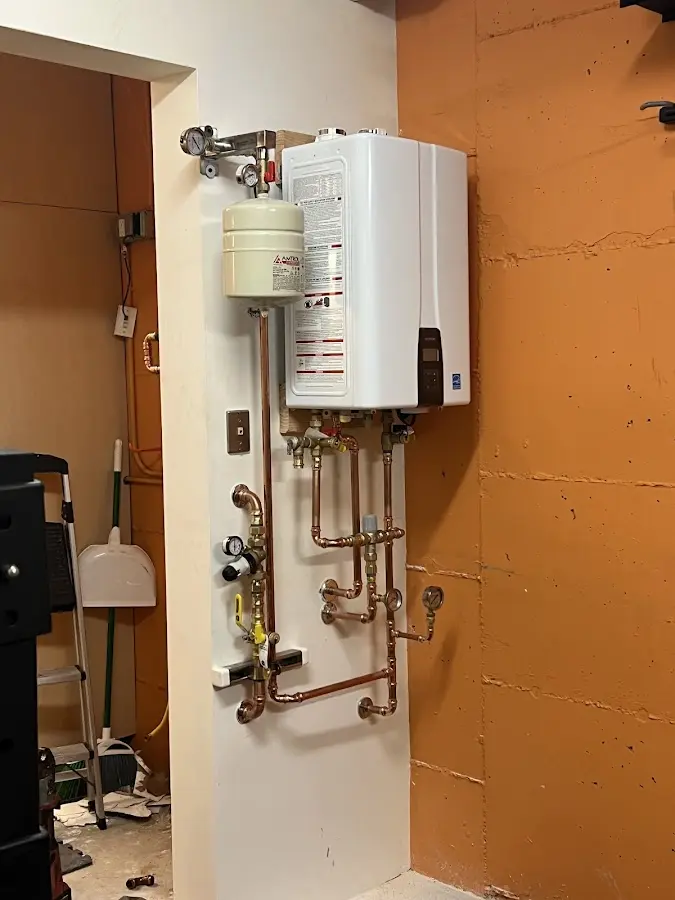 Plumbing technician inspecting water heater connections in Waltham